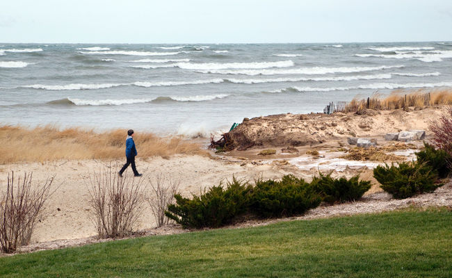 A resident walks along Ipperwash Beach on the shore of Lake Huron. Band members from the Kettle and Stony Point First Nation removed a barricade from Ipperwash Beach last week to allow cars to use the beach as a road to connect Kettle Point to Stony Point native communities, a move that has some residents up in arms. (CRAIG GLOVER, The London Free Press)